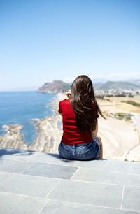 Rear view of woman looking at sea against clear sky