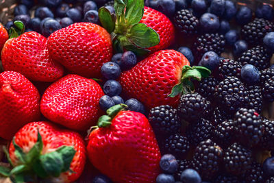 Woven basket of red strawberries, blueberries and blackberries