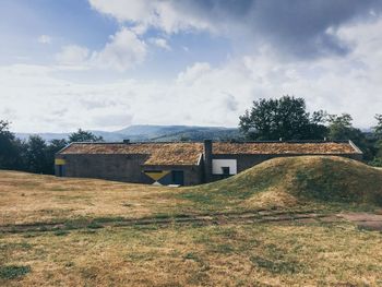 Old house on field against sky