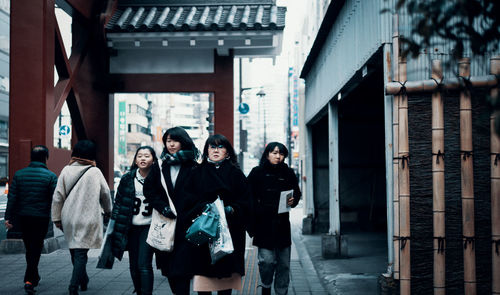 People walking on street amidst buildings in city