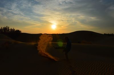 Man on sand dune against sky during sunset