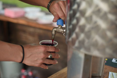 Cropped hand of woman filling glass with juice