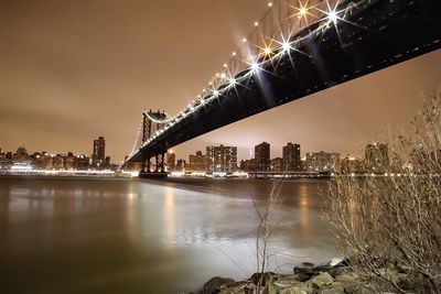 Low angle view of illuminated manhattan bridge over river at night