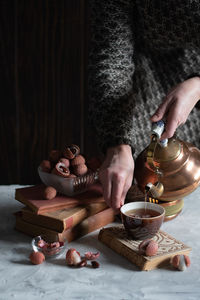 A woman pours tea from a copper teapot into a cup,still life with lychee,cozy