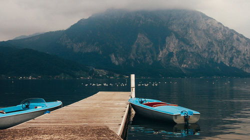 Boat moored on lake against mountains