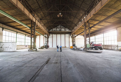 Two businessmen with documents talking in old industrial hall