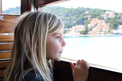 Close-up of girl looking through window