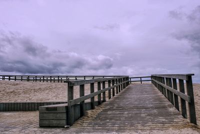 Footbridge over sea against sky