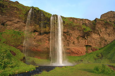 Scenic view of waterfall against sky