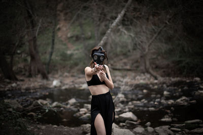 Full length of woman photographing in forest