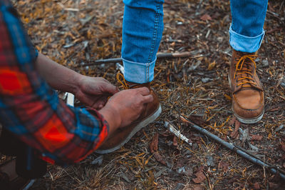 Close-up of man tying shoelace of friend on field