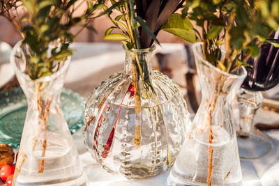 High angle of transparent glass vases with bunches of fresh flowers placed on table for event