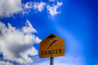 Close-up of road sign against blue sky