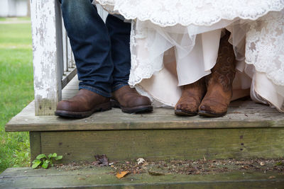 Low section of couple sitting on steps during wedding ceremony