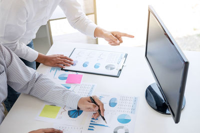 Cropped image of business people using computer at desk in office