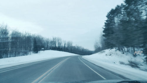 Road passing through snow covered trees