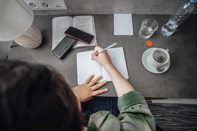Student deeply engaged in writing notes, learning, and concentration in serene study environment