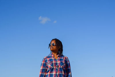 Low angle view of person standing against blue sky