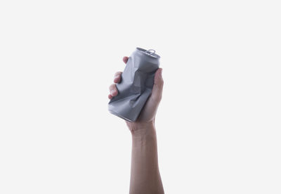 Cropped hand holding drink can against white background
