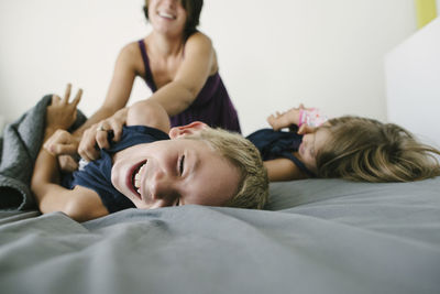 Happy mother playing with children on bed