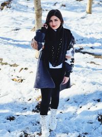 Portrait of young woman standing on snow covered field