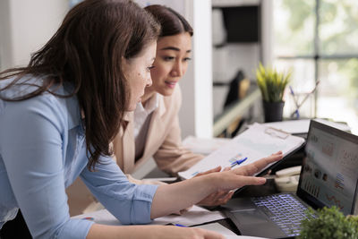 Side view of woman using laptop at office