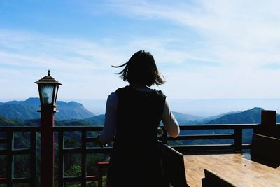 Rear view of woman looking at mountains against sky