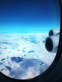 Airplane flying in sky seen through glass window