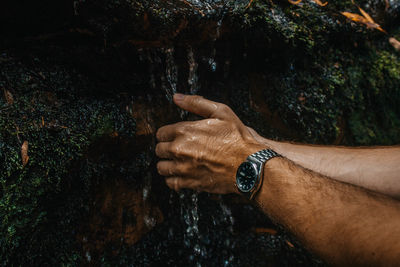 Cropped hand of man cleaning hand in flowing water