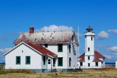 Exterior of old building by lighthouse against blue sky
