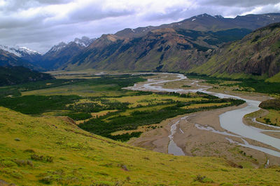 Scenic view of green landscape and mountains against sky