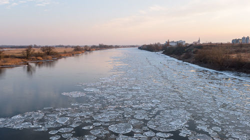 Scenic view of river against sky at sunset