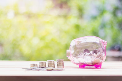 Close-up of piggy bank and coins on table