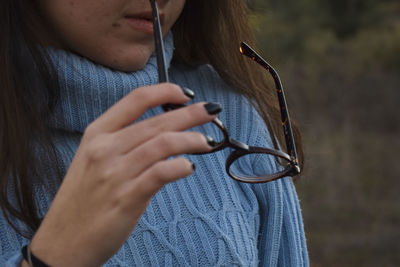 Midsection of woman holding eyeglasses