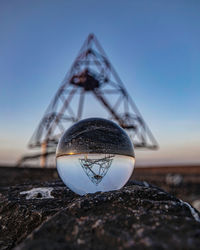 Close-up of crystal ball on field against sky