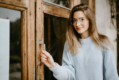 Portrait of smiling young woman standing against wood