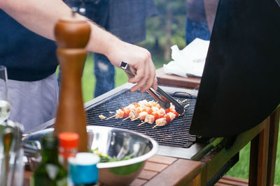 Close-up of man preparing food on barbecue grill