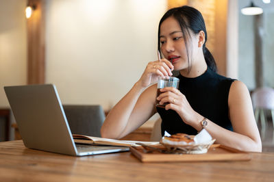 Young woman using mobile phone at table