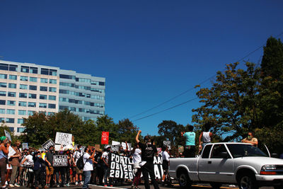 Group of people in city against clear blue sky