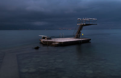 Floating platform in sea against cloudy sky at dusk