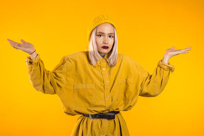 Portrait of woman standing against yellow background