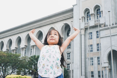 Portrait of girl standing against building in city