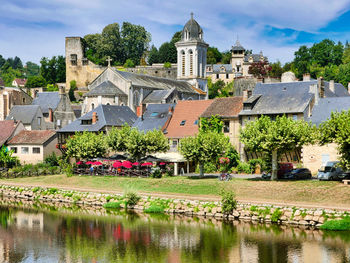 Houses by lake and buildings in town against sky