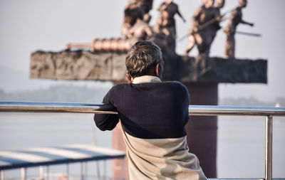 Rear view of man standing against railing