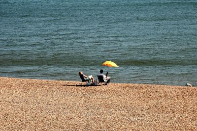 Rear view of couple relaxing on shore at beach