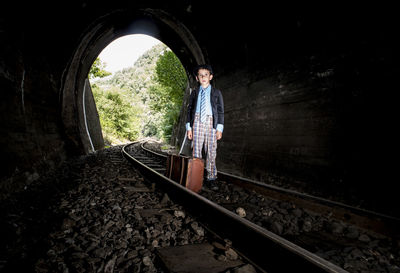 Portrait of boy standing on railroad track in tunnel