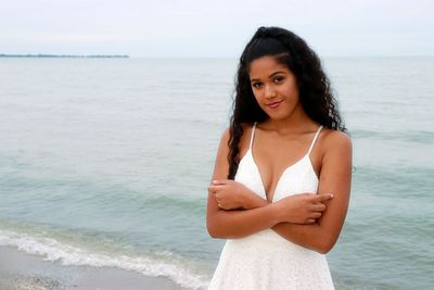 Portrait of beautiful young woman standing on beach