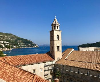 Buildings by sea against clear blue sky