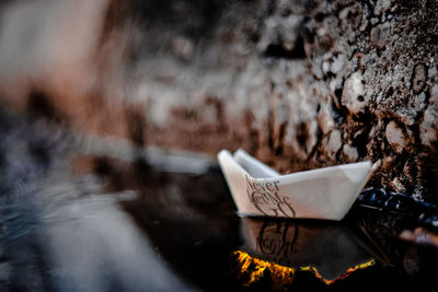 Close-up of paper boat with text in water