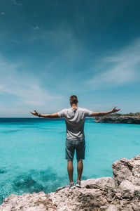 Rear view of young man standing against sea